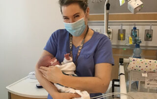 Dr. Maitre holds a NICU baby